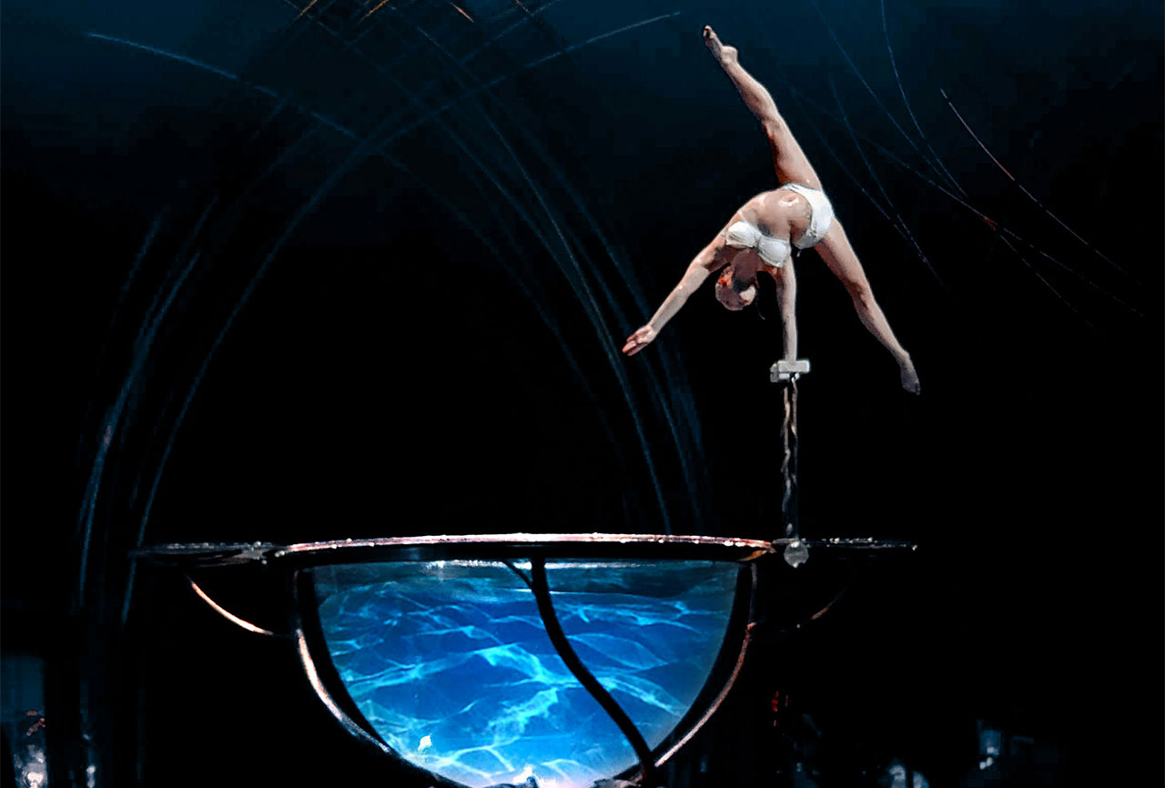 A dramatic shot of a Cirque du Soleil performer suspended high above a stage during a live production in Las Vegas.