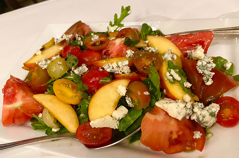 Heirloom tomato and peach salad with gorgonzola cheese and pesto vinaigrette