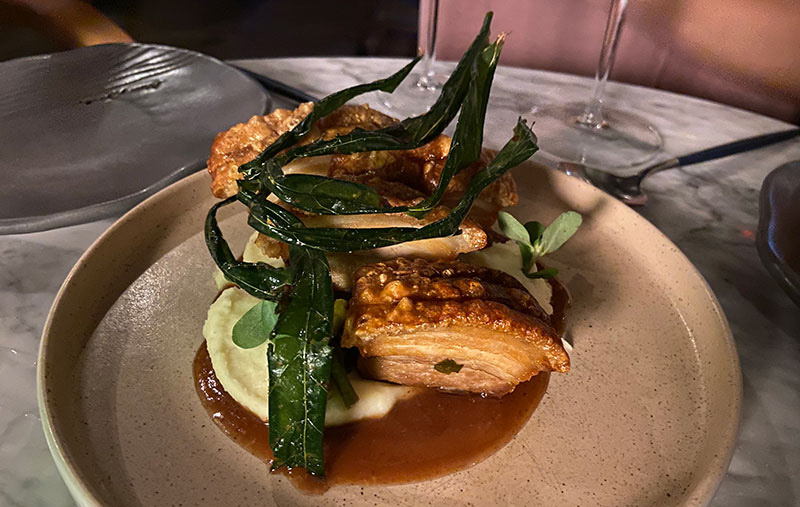 A gourmet plating of crispy fried pork belly served over creamy yam puree with tamarind sauce and crispy green garnishes at Mar y Zielo