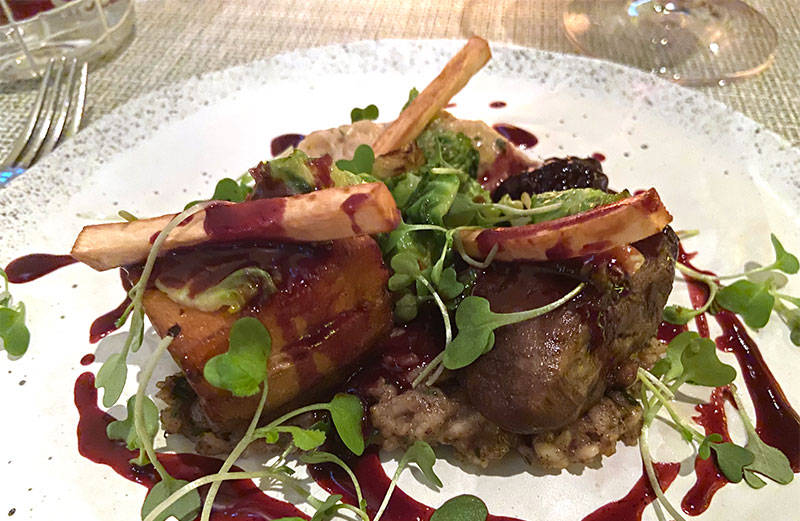 A beautifully plated fine dining dish featuring a piece of meat, root vegetable garnishes, and a rich dark sauce.