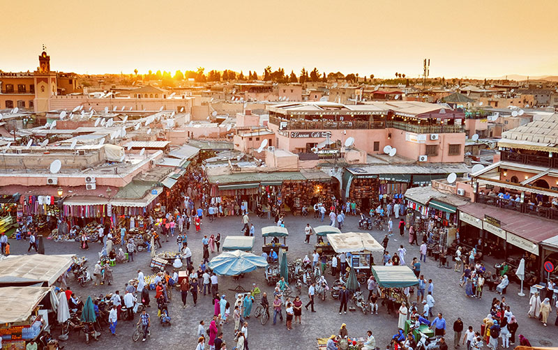 The bustling Jemaa el-Fnaa square in Marrakech at sunset with crowds and stalls.