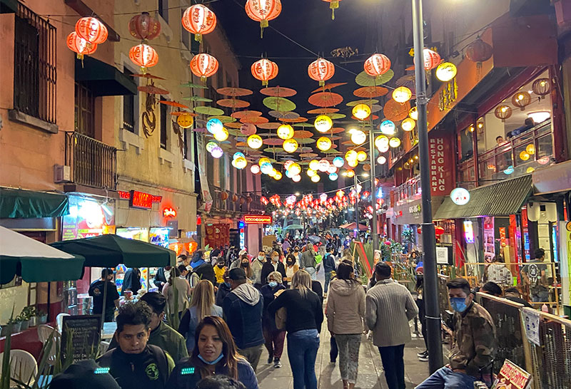 rowded street in Mexico City Barrio Chino at night with glowing red lanterns and street food vendors.