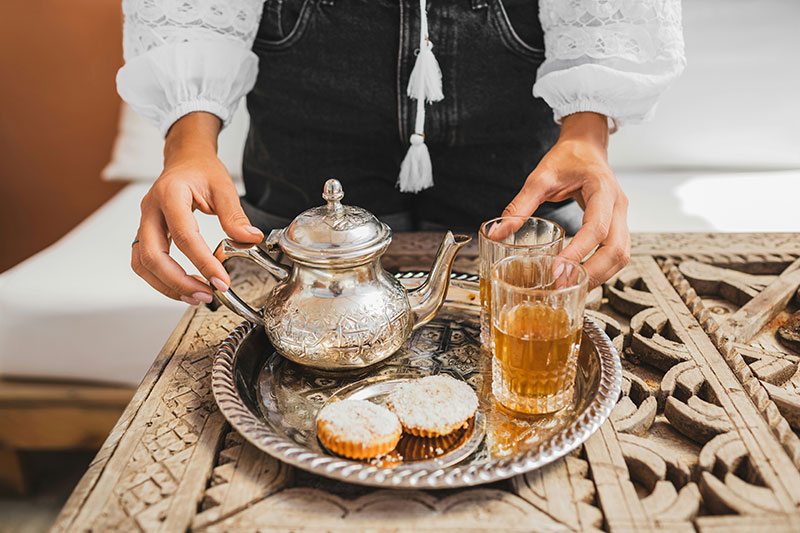 Traditional Moroccan mint tea being served from a silver teapot with almond pastries.