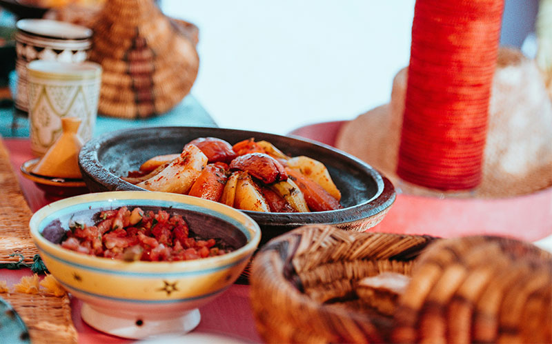 Traditional Moroccan vegetable tagine served in a clay pot on a colorful table.