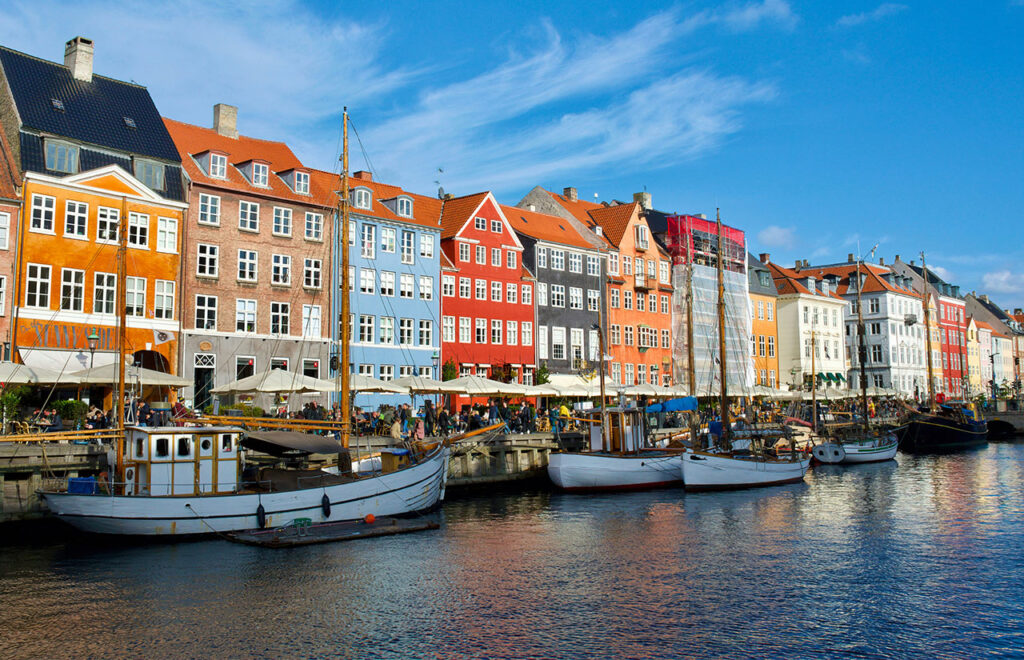 Brightly colored 17th-century townhouses and wooden ships lining the Nyhavn canal in Copenhagen, Denmark.