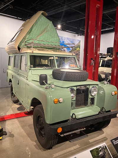 Vintage 1966 green Land Rover Series IIA with a custom pop-up roof tent.