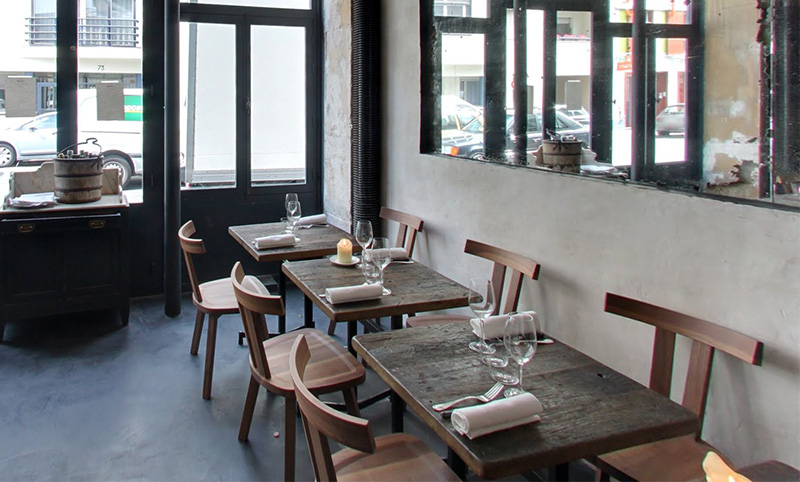 The minimalist and rustic interior of Septime restaurant in Paris, featuring wooden tables, industrial windows, and a clean, unpretentious dining space.