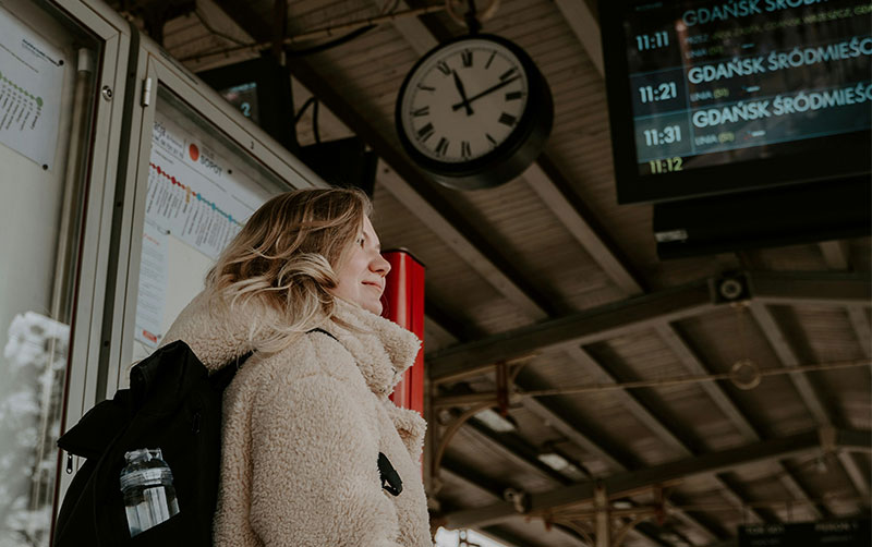 confident young woman standing on a train station platform.