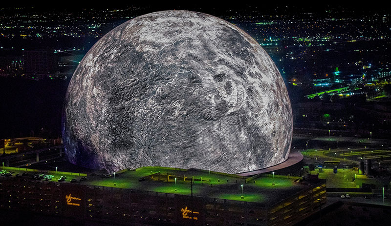 A nighttime view of The Sphere in Las Vegas, illuminated with a high-resolution image of the moon, glowing against the dark sky
