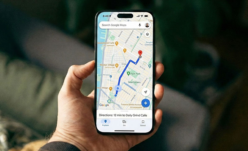 A person's hand holding an iPhone displaying walking directions on the Google Maps app towards a destination in Manhattan. The screen shows a blue navigation route and travel planning text, illustrating seamless itinerary management.