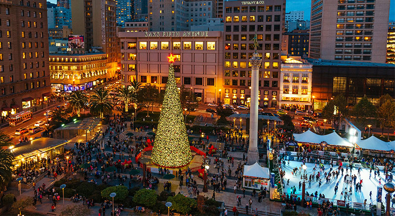 An aerial view of the large illuminated Christmas tree and ice skating rink at Union Square in San Francisco at dusk