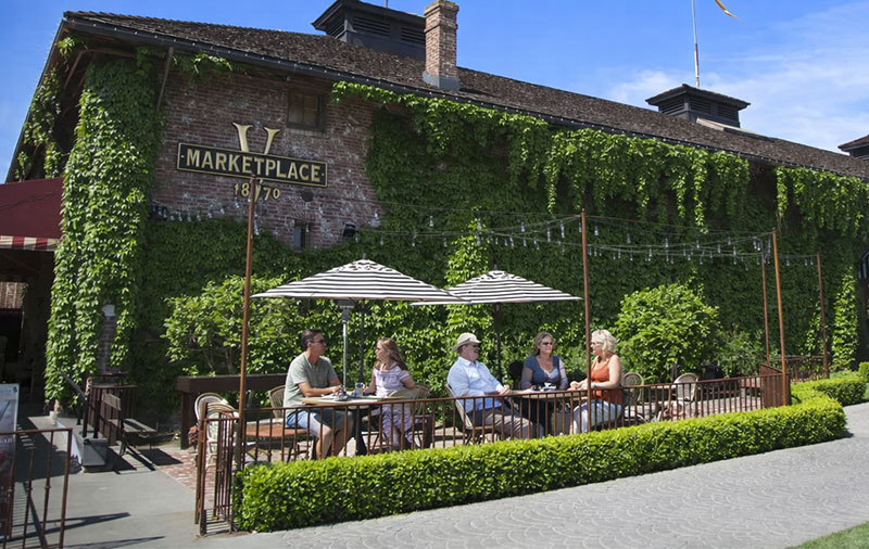 Outdoor patio at V Marketplace in Yountville Napa Valley with ivy covered historic building and people dining