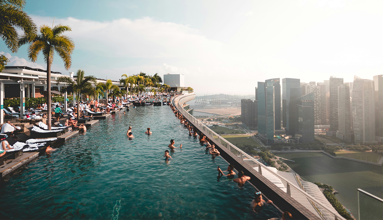 An infinity pool overlooking the Singapore city skyline and the Marina Bay Sands hotel at sunset.