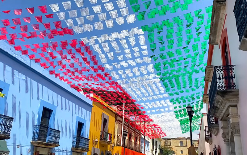 Colorful streets of Jalatlaco Oaxaca with red white and green flags overhead