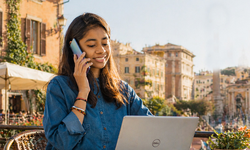 A close-up view of various travel essentials including an iPhone, an American Express credit card, a Capital One card, and several Euro banknotes, highlighting the importance of digital and financial security for travelers.