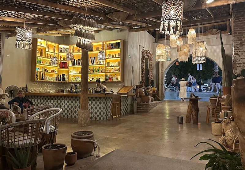 An upscale and colorful restaurant interior with high ceilings, decorative hanging lanterns, and traditional Mexican decor including clay pots and wooden furniture at Don Sánchez Restaurant in San José del Cabo