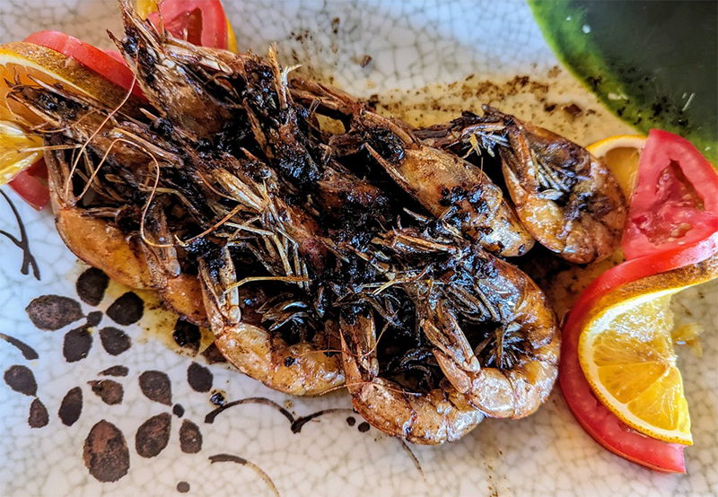 A close-up of a vibrant seafood platter from Mariscos Las Tres Islas, featuring chilled shrimp and a fresh octopus salad garnished with lime and cucumber slices.