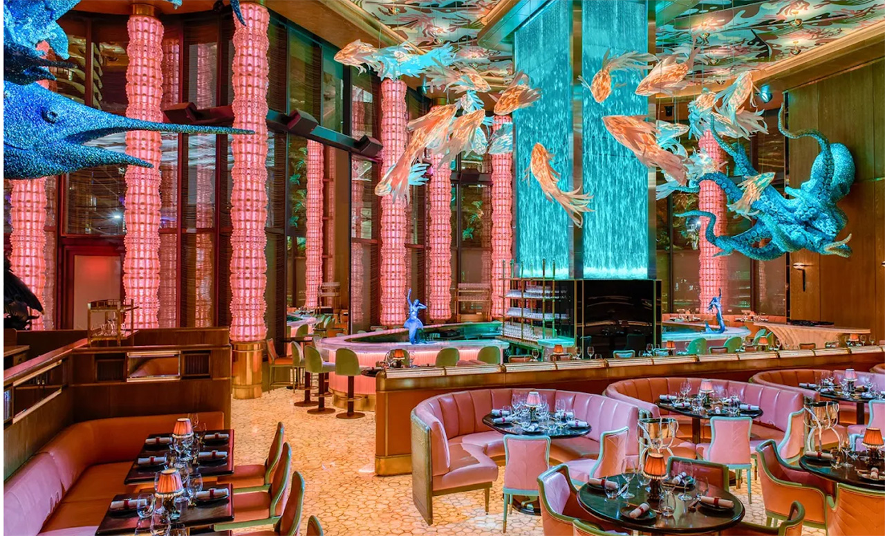 Vibrant interior of Sexy Fish restaurant in Brickell, Miami, featuring ornate fish-themed chandeliers, colorful underwater-inspired murals, and plush pink seating.