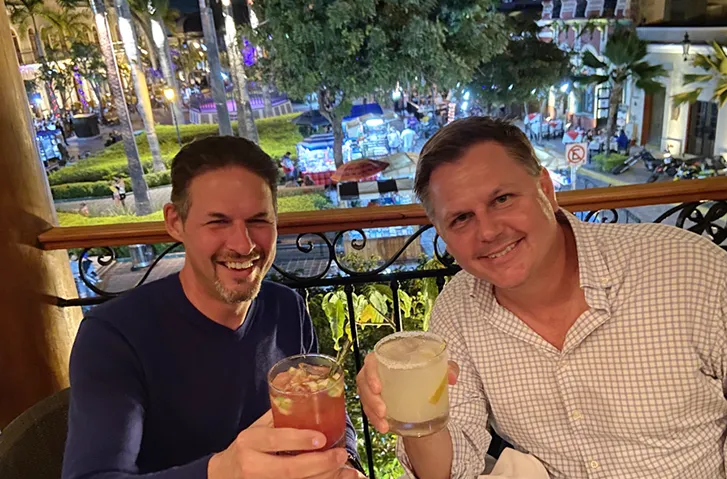 Corey and Aaron smiling at a dining table with drinks at Casa 46 in Centro Histórico, Mazatlán.