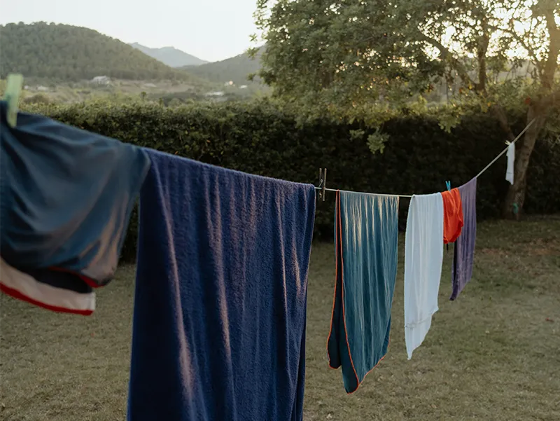 Travel clothes drying on an outdoor clothesline against a blue sky.