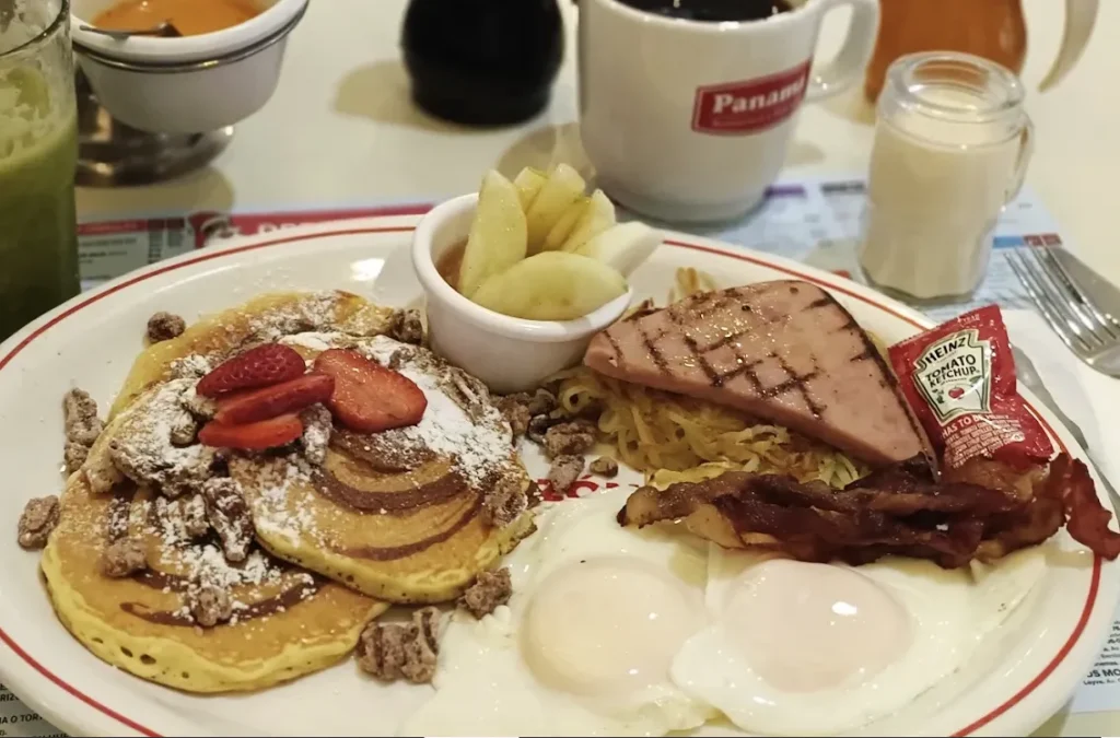 A traditional Mexican breakfast plate, a basket of bread, and a cup of coffee on a table at Panamá Restaurante y Pastelería.