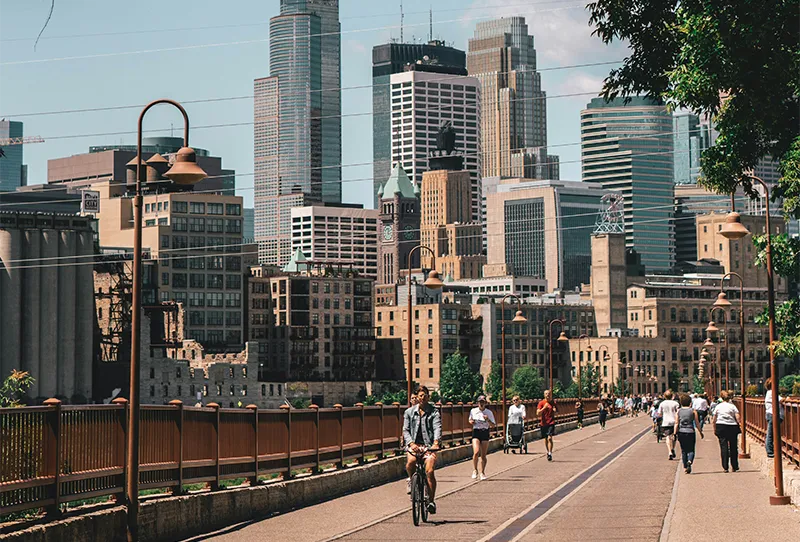 Historic Stone Arch Bridge crossing the Mississippi River with the downtown Minneapolis skyline in the background.
