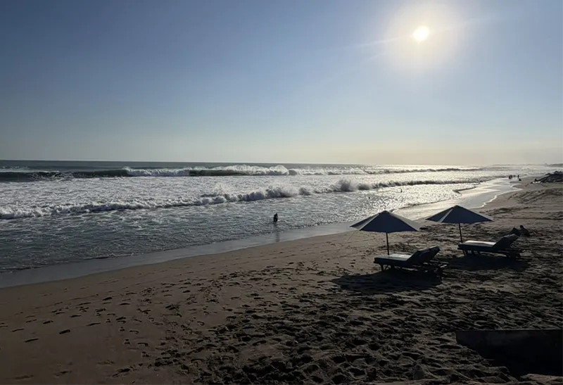 Golden sand and gentle ocean waves under an open sky along the coastline in Bali.