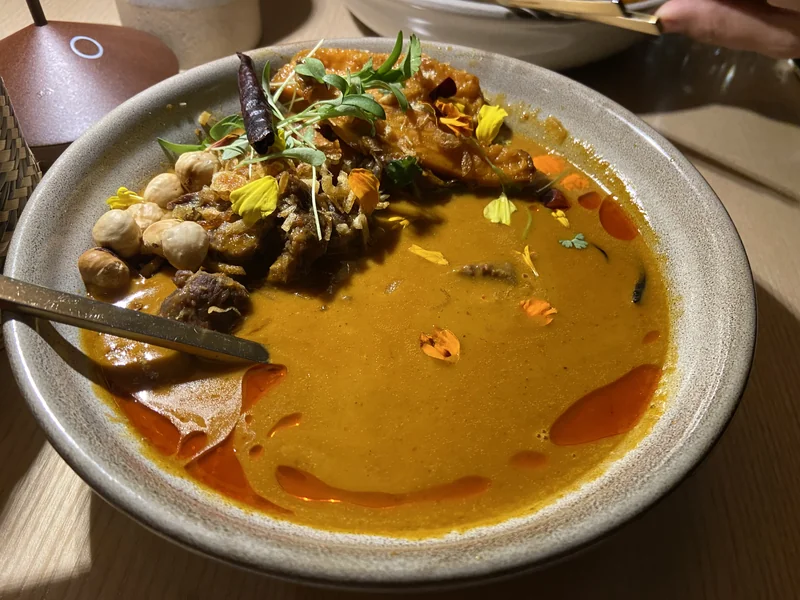 Massaman curry with brisket, nuts and garnishes in a wide bowl at Khâluna.
