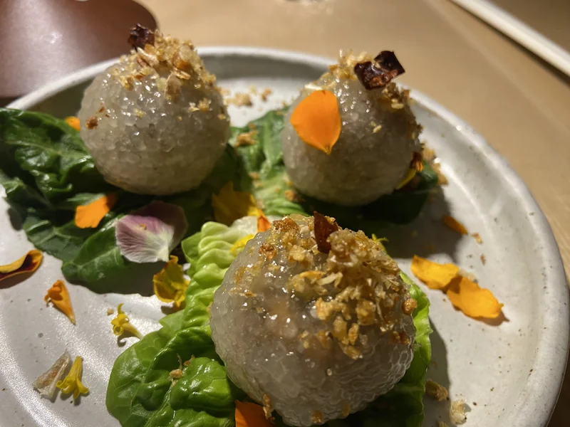 Sakoo tapioca dumplings on lettuce with crushed nuts and flower petals at Khâluna in Minneapolis.