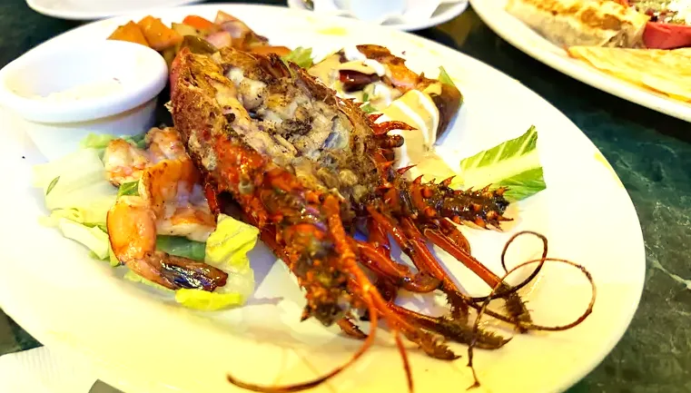 A split, grilled whole lobster served on a yellow plate at Pancho's Restaurant in Mazatlán.