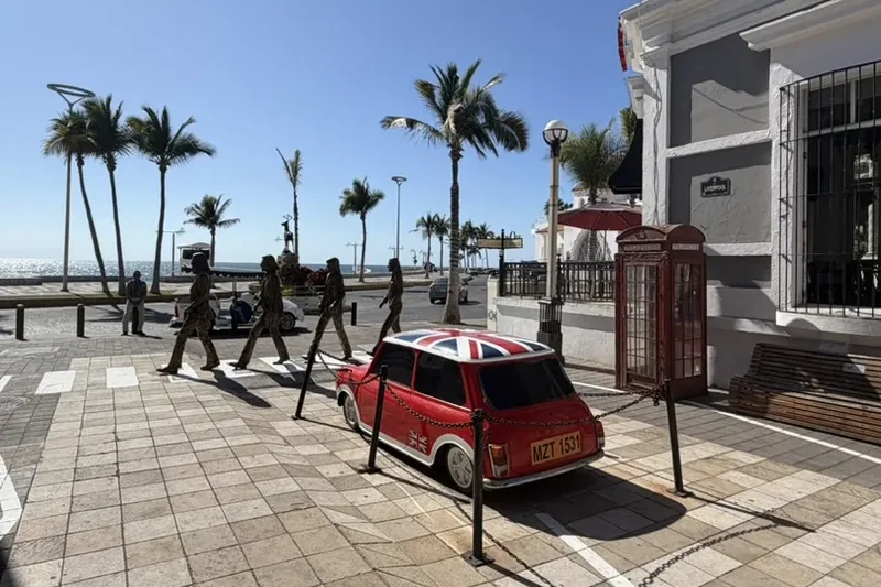 Beatles figures at a zebra crossing beside a red Mini and telephone box in Liverpool Alley, Mazatlán.
