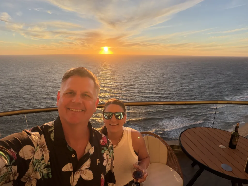 Corey and Melissa seated at an outdoor table overlooking the ocean at sunset in Mazatlán.