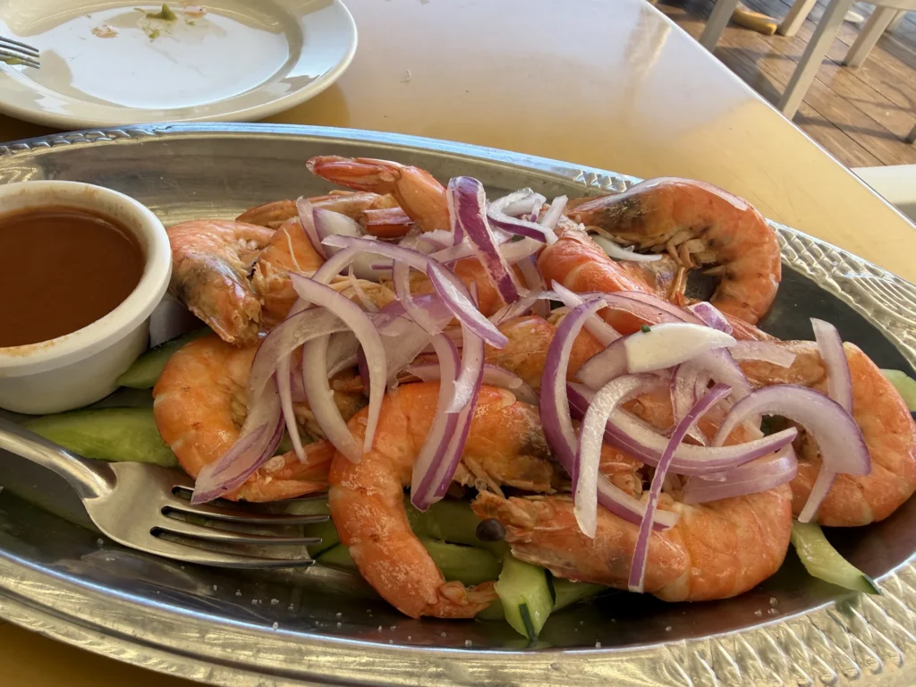 Platter of whole cooked shrimp with red onion, vegetables, and dipping sauce in Mazatlán.