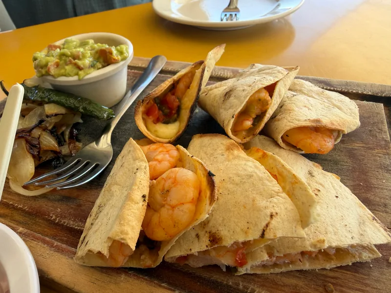 A plate of grilled Tacos Gobernador filled with shrimp and melted cheese, served with a side of guacamole at La Puntilla Seafood Restaurant in Mazatlán.