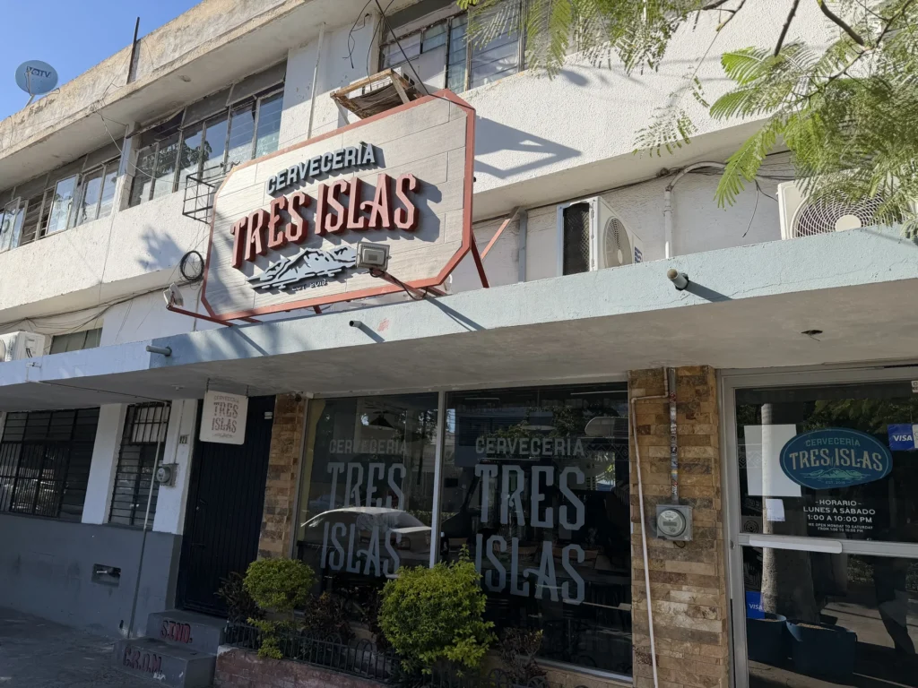 Street view of Tres Islas Brewery with its name displayed above the entrance in Mazatlán.