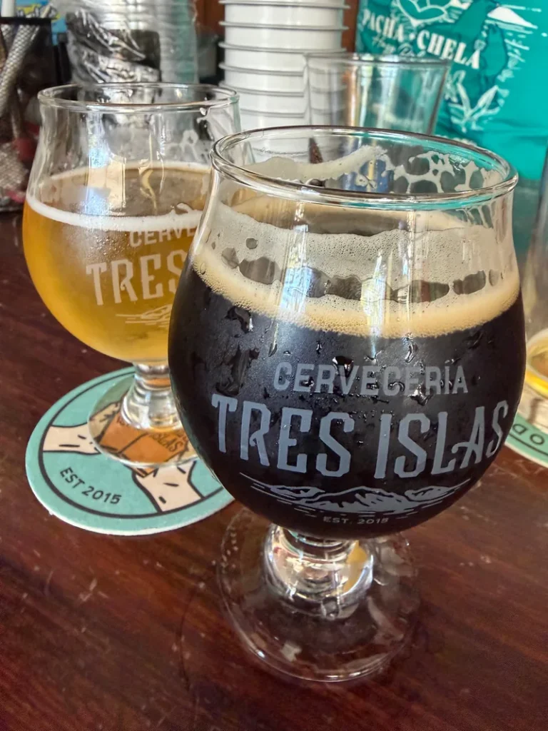 Two glasses of craft beer on a wooden table at Cervecería Tres Islas in Mazatlán.