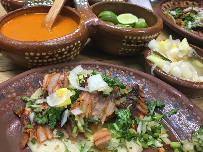 Al pastor tacos topped with pineapple, onion and cilantro, with salsas and lime at Pancho’s Takos.